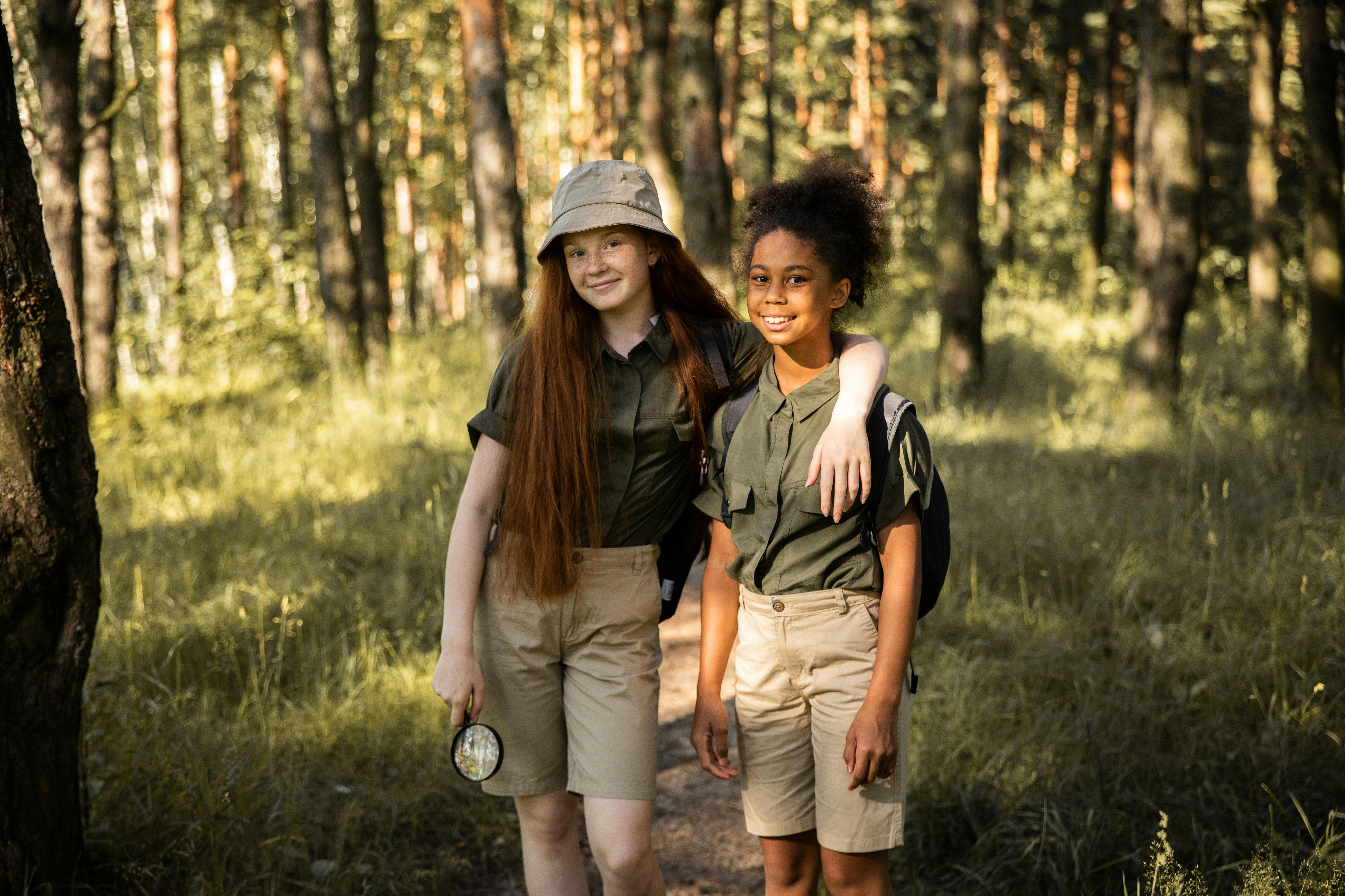 two teenage girls smiling at the camera in a forest